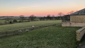 A rural landscape with a stone building, a fenced field, and a sheep grazing. - Hundith Hill Hotel (Cockermouth)