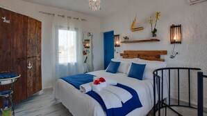 Una camera da letto con un letto, un'armadio in legno, un tavolino con una sedia, una finestra con tende e luci a parete.