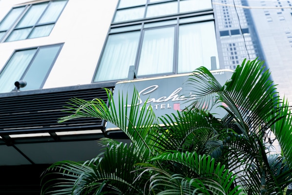 A hotel sign with the name 'Chic Hotel' in front of a modern building with large windows.