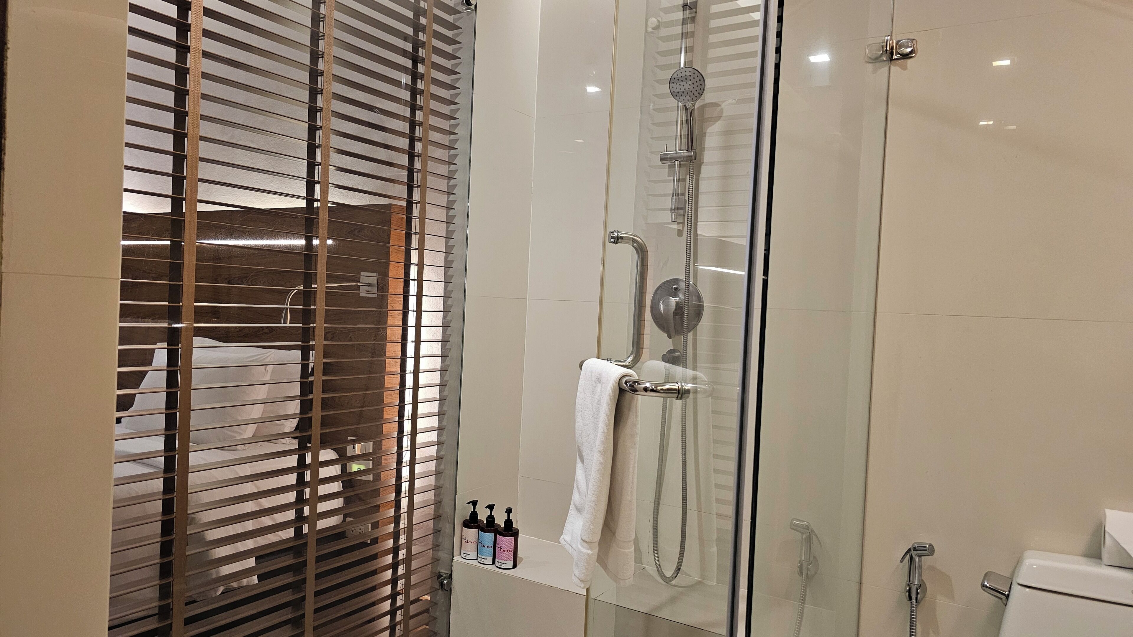 Ein begehbares Duschbad mit Handbrause, Handtuchhalter und Toilette zur Rechten.