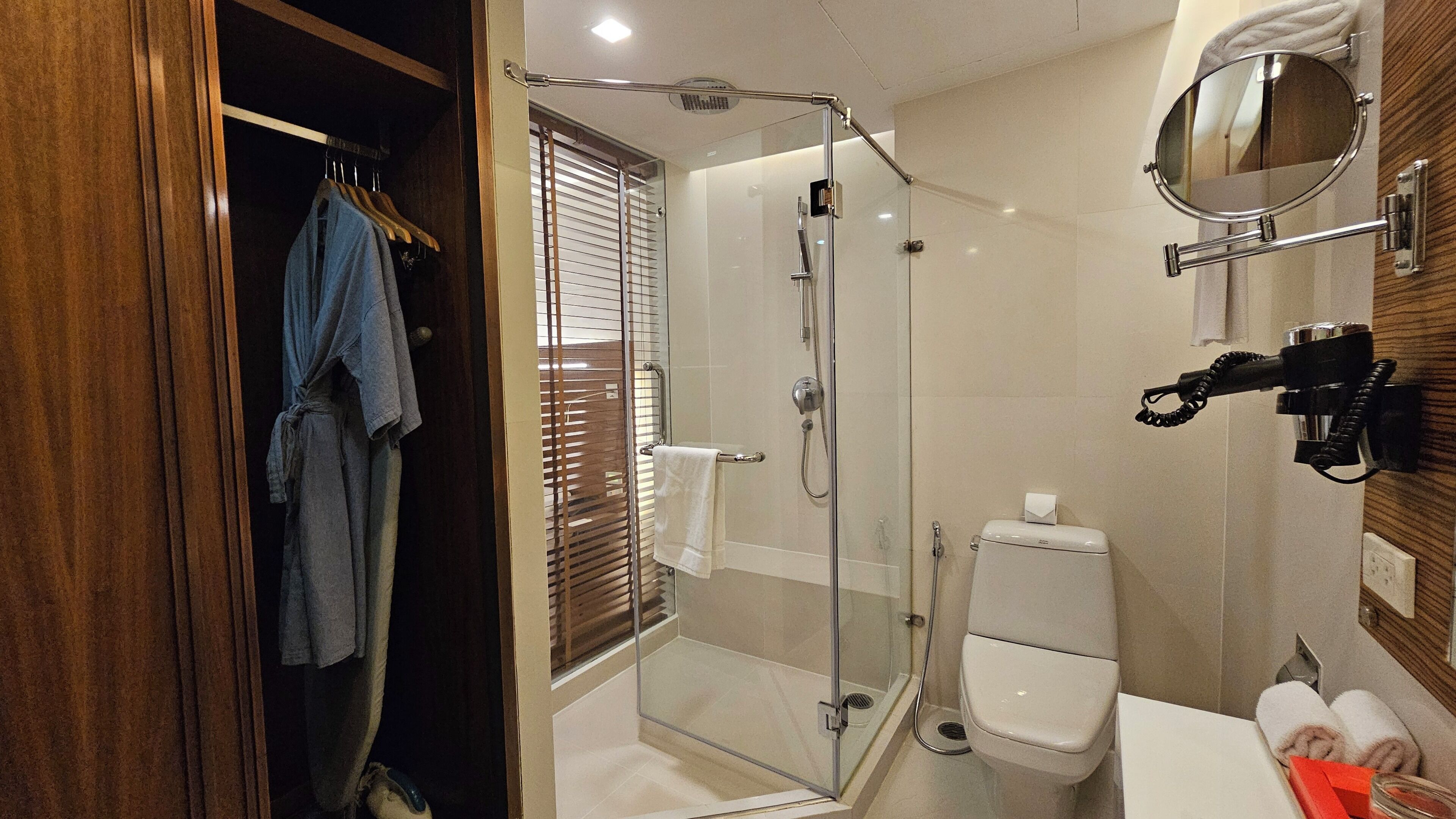 A bathroom with a glass-enclosed shower, a toilet, and a sink with a mirror.