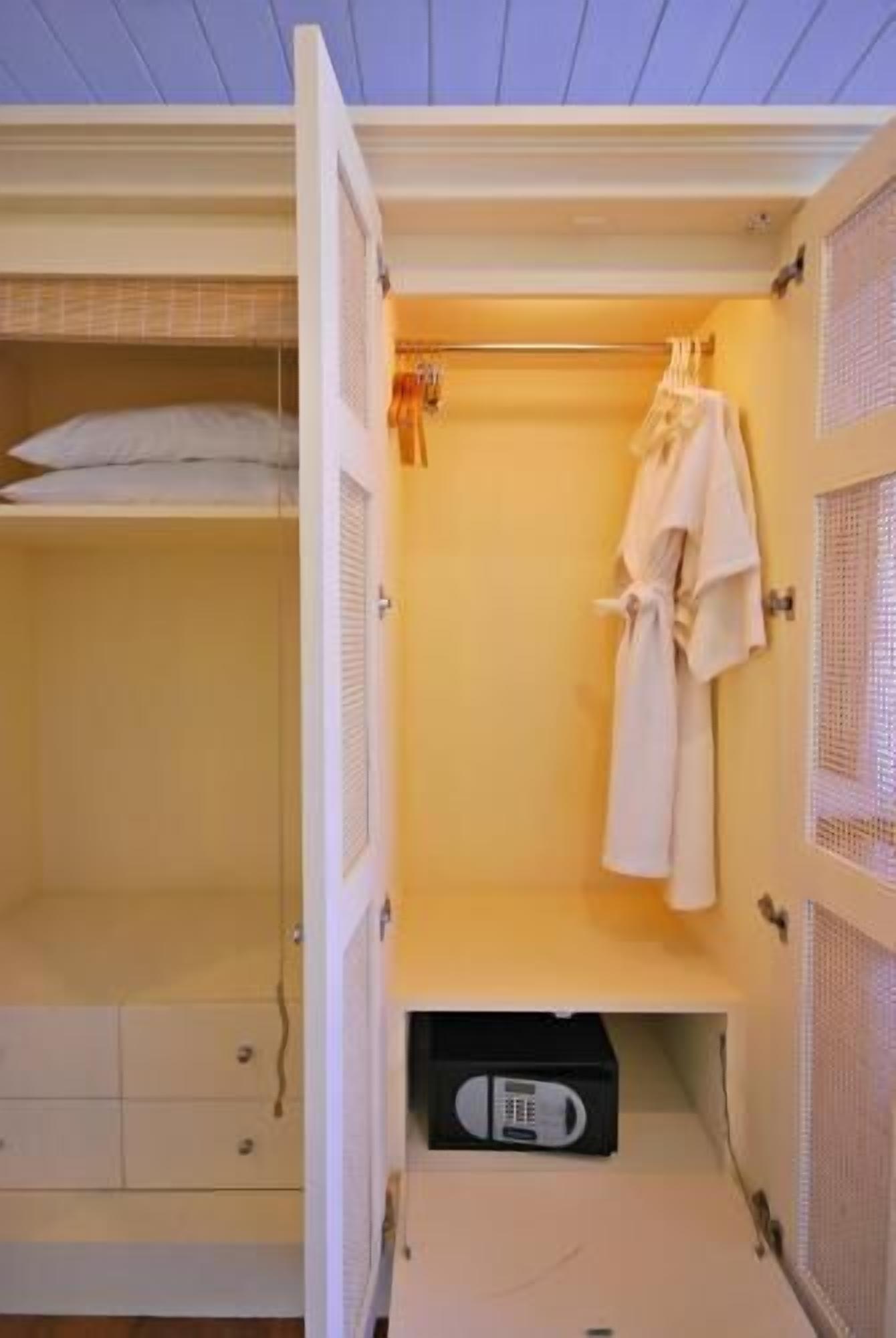 A walk-in closet with a bed, hanging clothes, and a microwave.