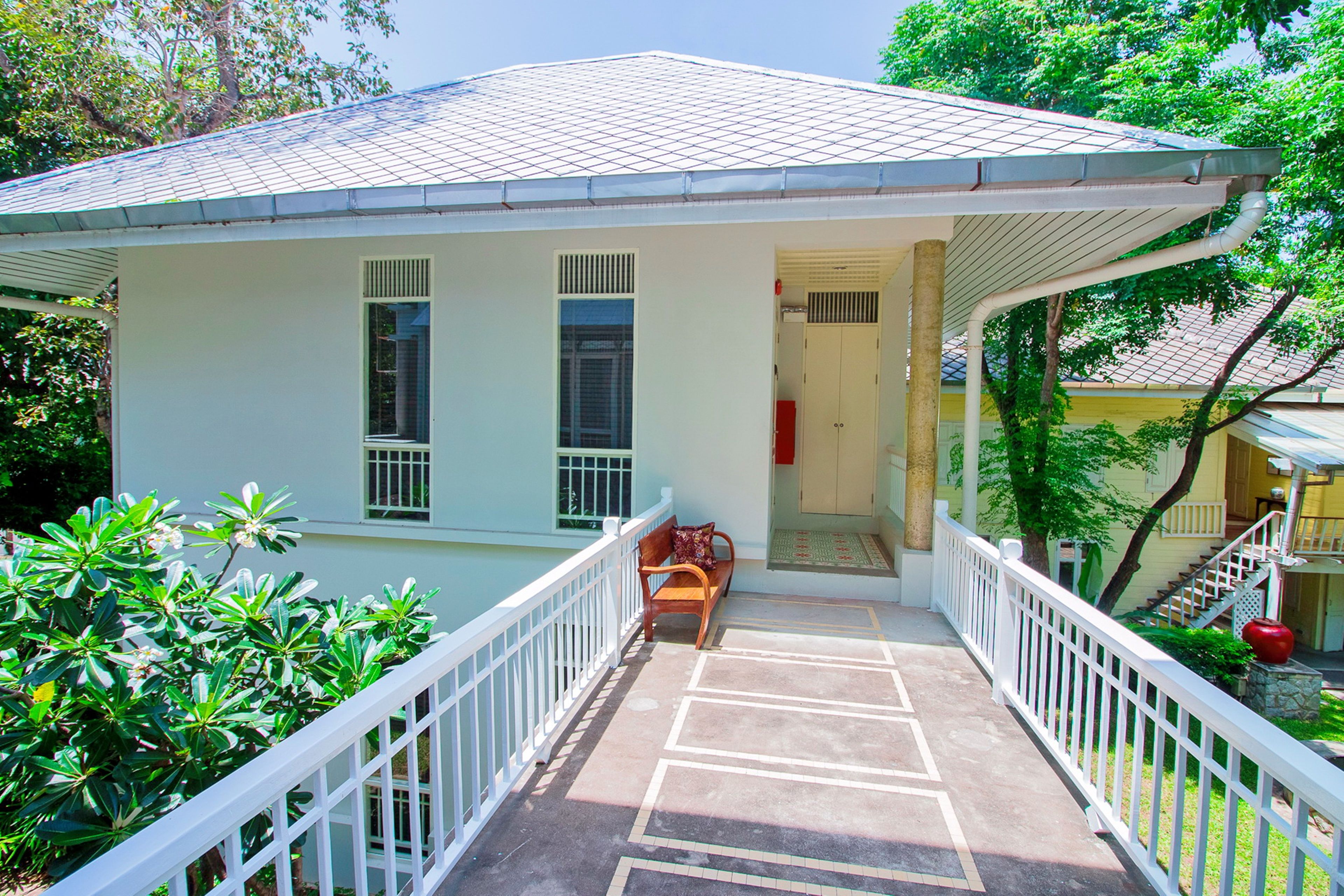 A two-story building with a covered porch, white railings, and a bench.