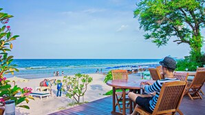 A wooden deck with outdoor seating overlooking a beach. - Baan Bayan Beach Hotel (Hua Hin)