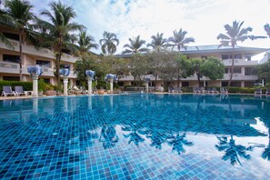 A swimming pool with tiled flooring, surrounded by palm trees and lounge chairs. - Golden Beach Resort (Krabi)