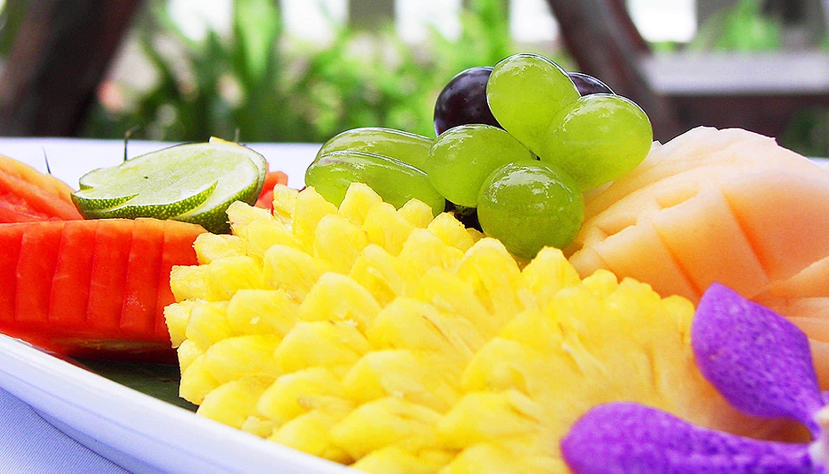 Une assiette de fruits variés, notamment de la pastèque, de l’ananas, des raisins et du melon.
