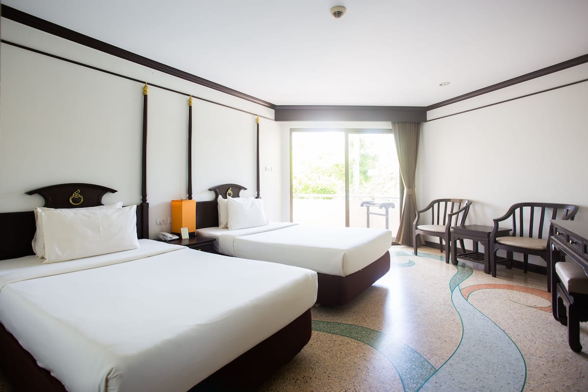 A hotel room with two beds, a desk, and a chair.