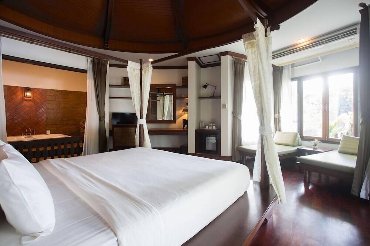 Une chambre d’hôtel avec un grand lit, une salle de bain avec un miroir, un bureau et une fenêtre.