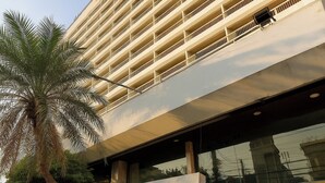 A hotel with a modern facade, a palm tree in front, and a sign with Chinese characters. - Pailyn Hotel Phitsanulok (Phitsanulok)