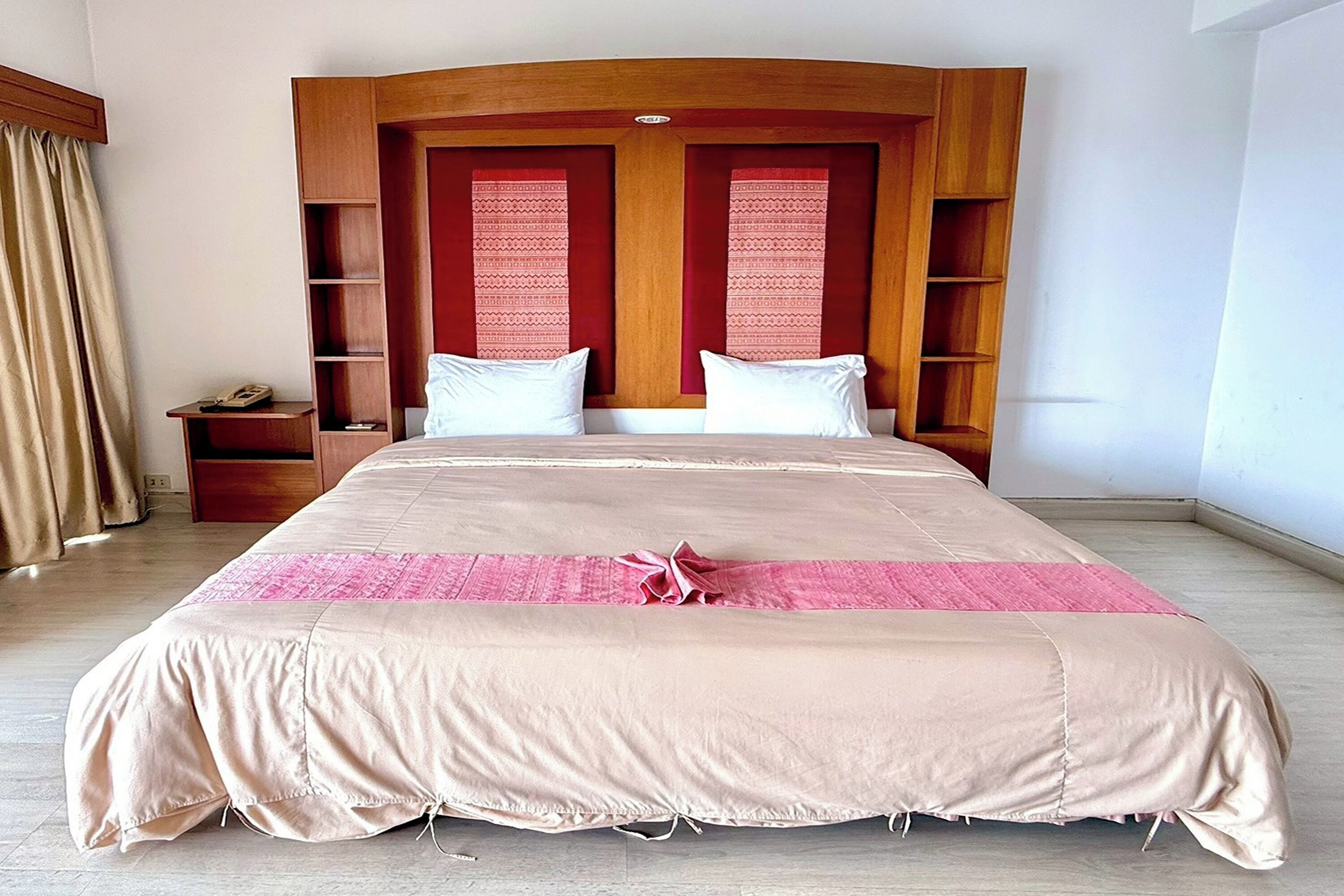 A large bed with a wooden headboard, two bedside tables, and a pink decorative item on the bed.