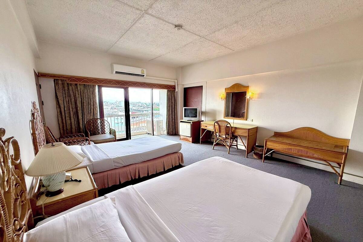 A hotel room with two beds, a desk, a chair, a TV, and a window with a view.