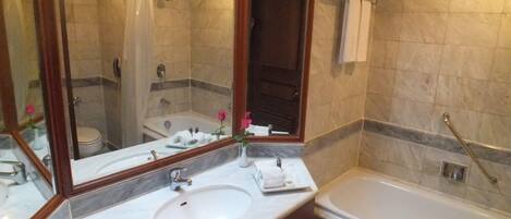 A bathroom with a marble sink, a bathtub, and a shower area.