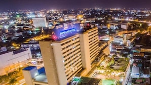 Un hotel con varios pisos, una piscina en la azotea y un entorno urbano bien iluminado.