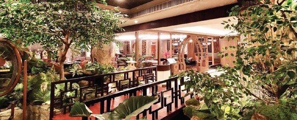 Un jardin intérieur avec un pont en bois, des plantes en pot et un espace détente offrant une vue sur la pièce.