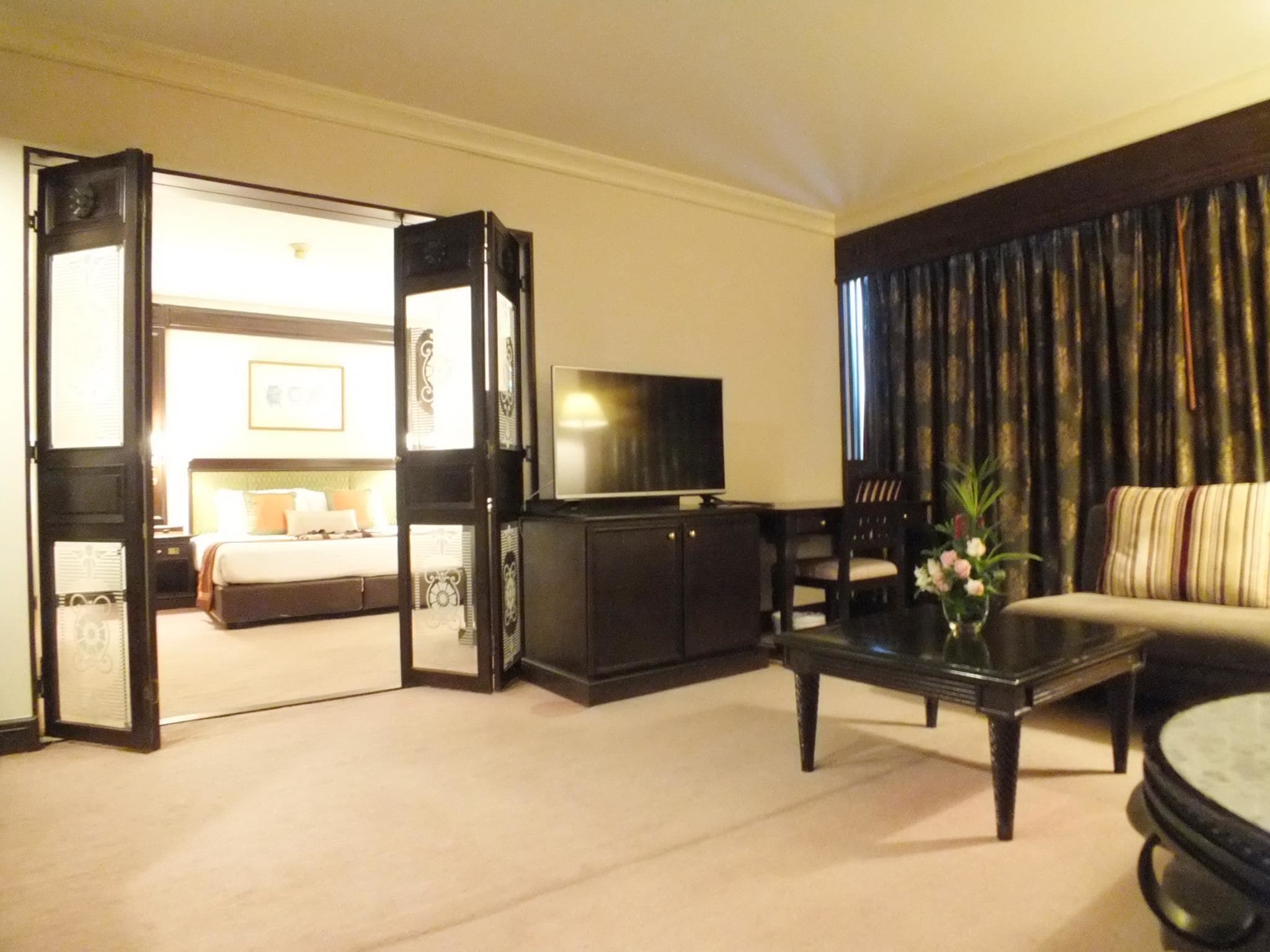 Una habitación de hotel con una cama, televisión, sofá y mesa de centro.