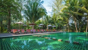 A pool area with lounge chairs and umbrellas, surrounded by palm trees. - Haadson Resort (Takua Pa)