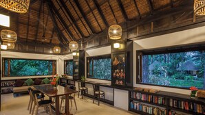 A library with bookshelves, a dining table, and chairs. - Haadson Resort (Takua Pa)