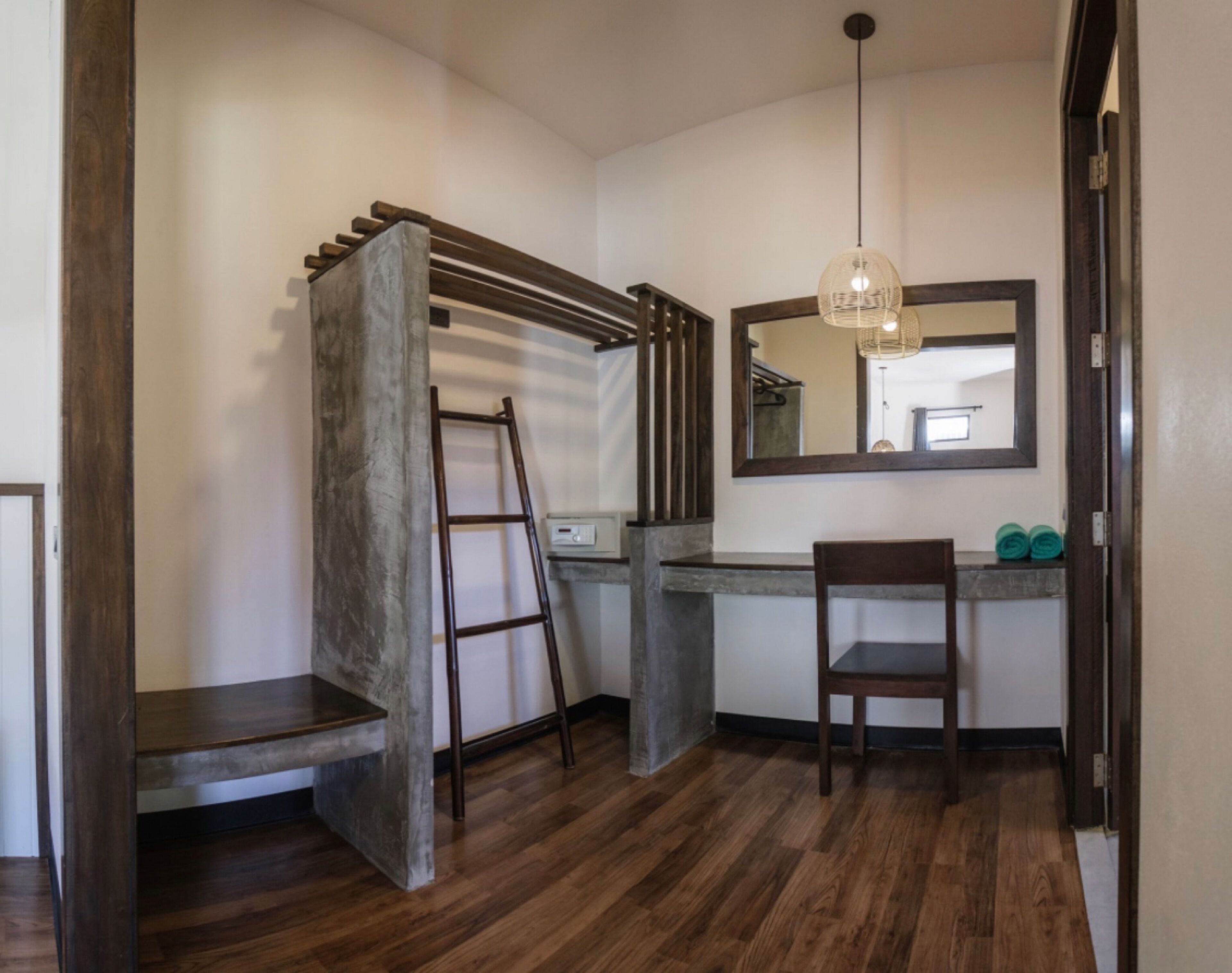 Un baño con un banco de madera, una escalera, un espejo y una lámpara colgante.