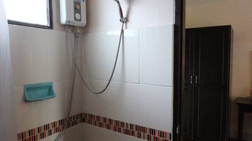 Un baño pequeño con azulejos blancos, una ducha, un ventanal y suelo de madera.