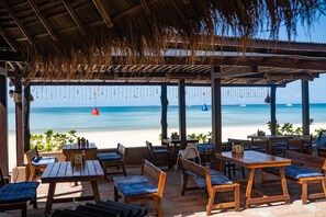 A beachside patio with wooden tables and benches, overlooking the ocean. - Southern Lanta Resort (Ko Lanta)