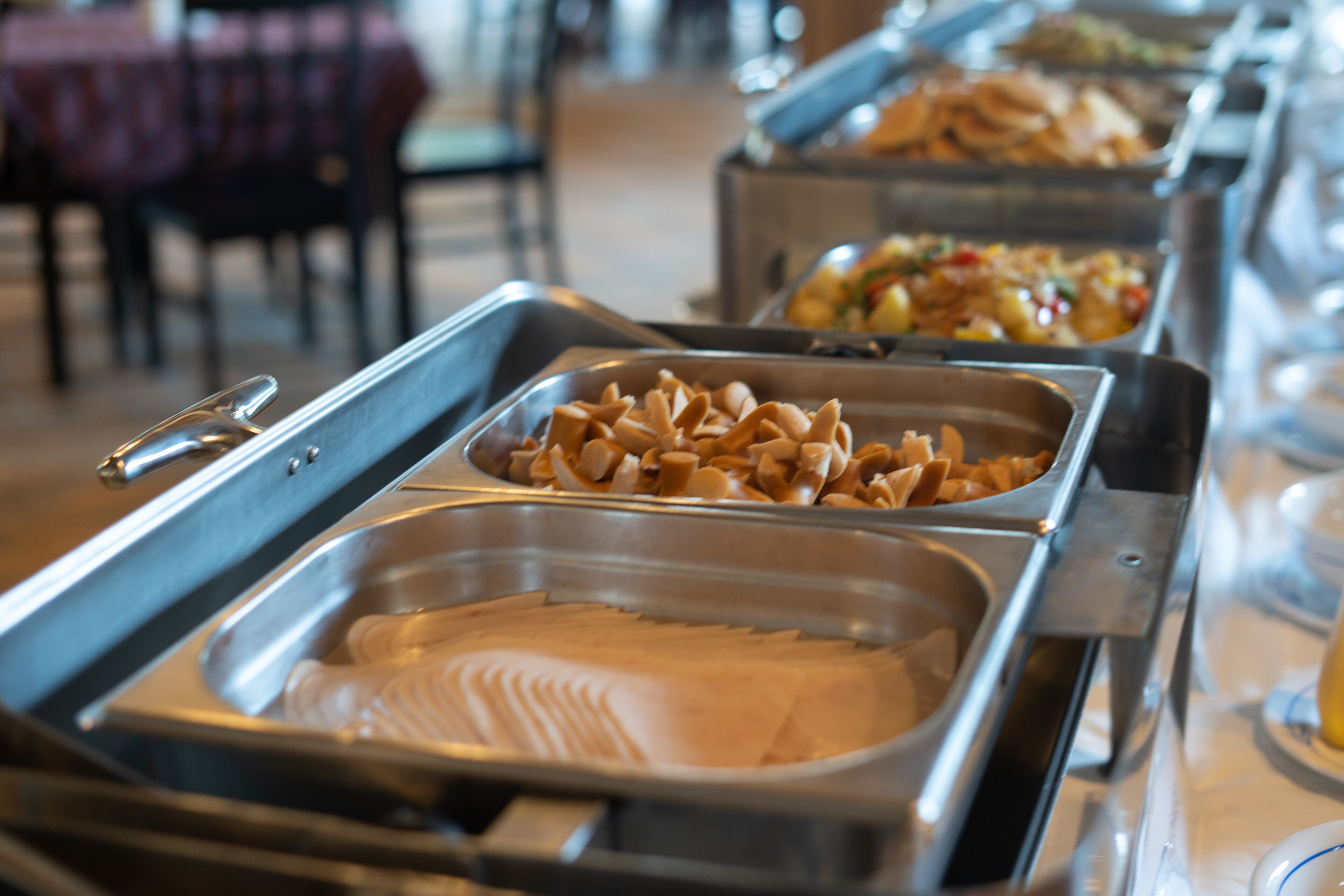 A buffet with various food items in metal serving trays.