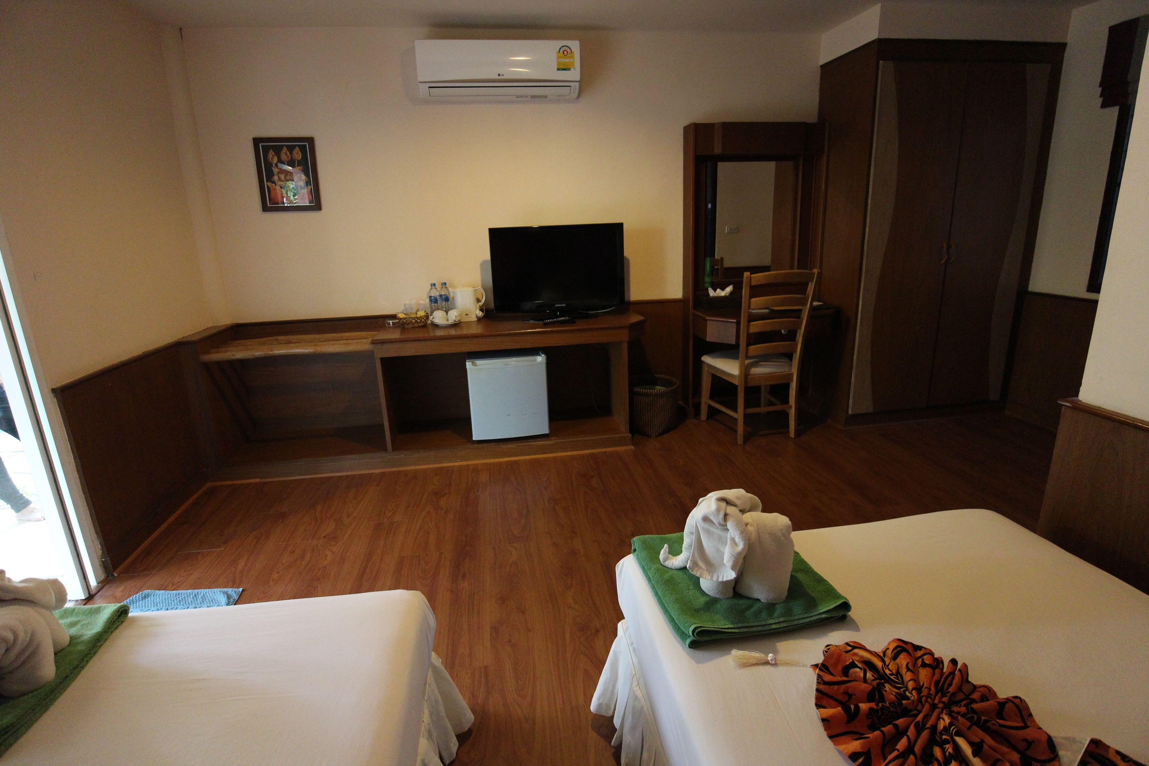 Una habitación de hotel con cama, escritorio con televisor, silla y armario.