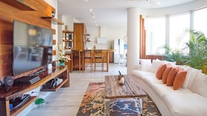Ein modernes Wohnzimmer mit Flachbildfernseher, Holz-Unterhaltungseinheit, weißem Sofa und Couchtisch.