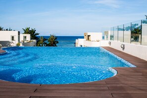 A swimming pool with a view of the ocean, surrounded by palm trees and modern architecture. - 7Stones Boracay (Boracay Island)