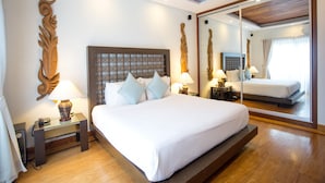 Ein Hotelzimmer mit einem großen Bett, einem Holz-Kopfteil, zwei Nachttischen mit Lampen, einem großen Spiegel und einem Holzboden.