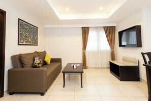 A living room with a sofa, a coffee table, a flat-screen TV mounted on the wall, and a window with curtains. - Club Mahindra Mac Boutique Hotel  (Bangkok)