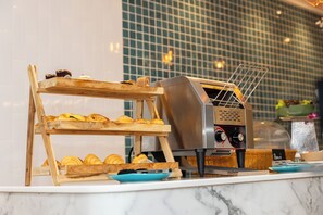 A bakery display with pastries and a coffee machine. - Club Mahindra Mac Boutique Hotel  (Bangkok)