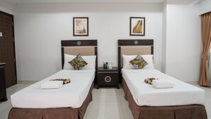 A hotel room with two beds, each with a brown skirted base, white bedding, and decorative pillows. There are framed pictures on the wall above each bed. - Club Mahindra Mac Boutique Hotel  (Bangkok)