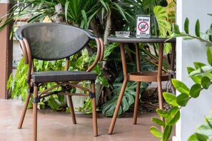 A chair and a small table with a 'NO WEED ZONE' sign, surrounded by lush green plants. - Club Mahindra Mac Boutique Hotel  (Bangkok)