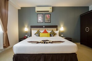 A hotel room with a large bed, two bedside tables, an air conditioning unit, and framed pictures on the wall. - Club Mahindra Mac Boutique Hotel  (Bangkok)