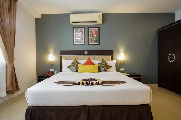 A hotel room with a large bed, two bedside tables, an air conditioning unit, and framed pictures on the wall. - Club Mahindra Mac Boutique Hotel  (Bangkok)