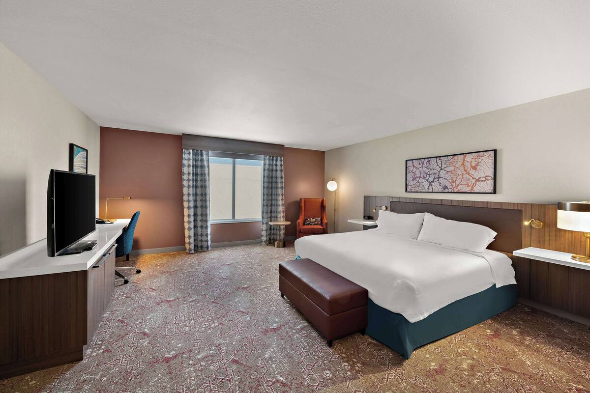 Une chambre d’hôtel avec un grand lit, un bureau équipé d’un ordinateur, une télévision et une chaise.