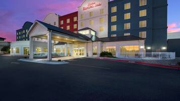 A multi-story hotel with a prominent entrance and a covered parking area.