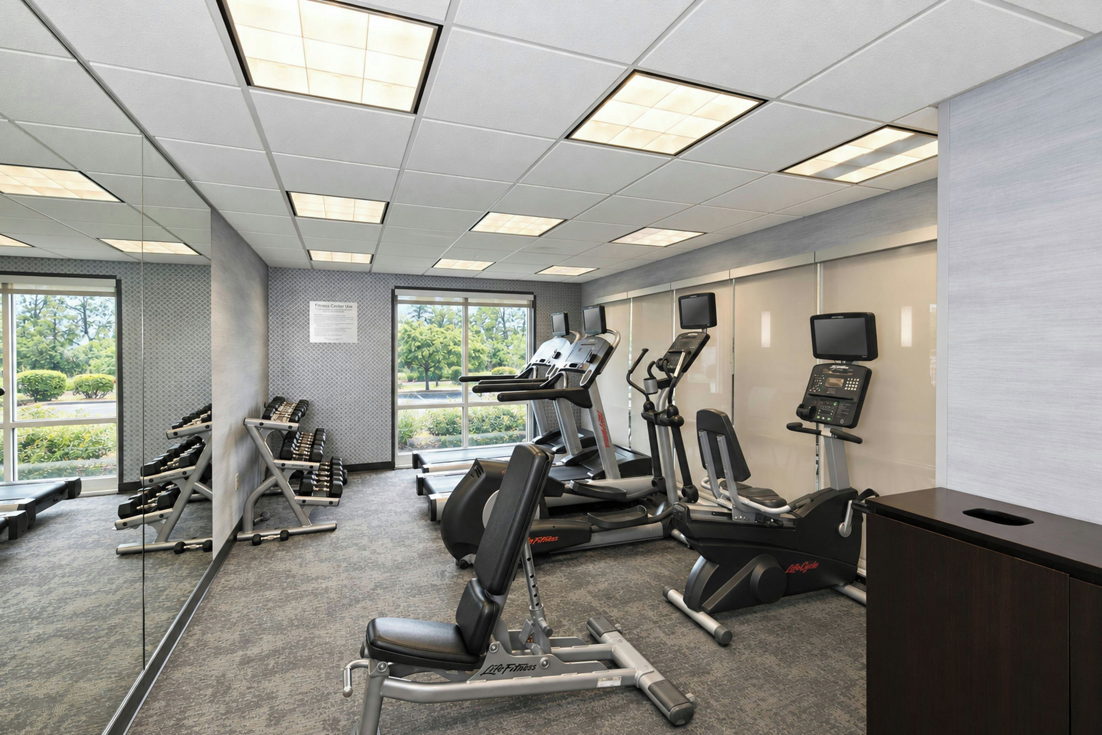 A fitness center with treadmills, elliptical machines, and weight benches.