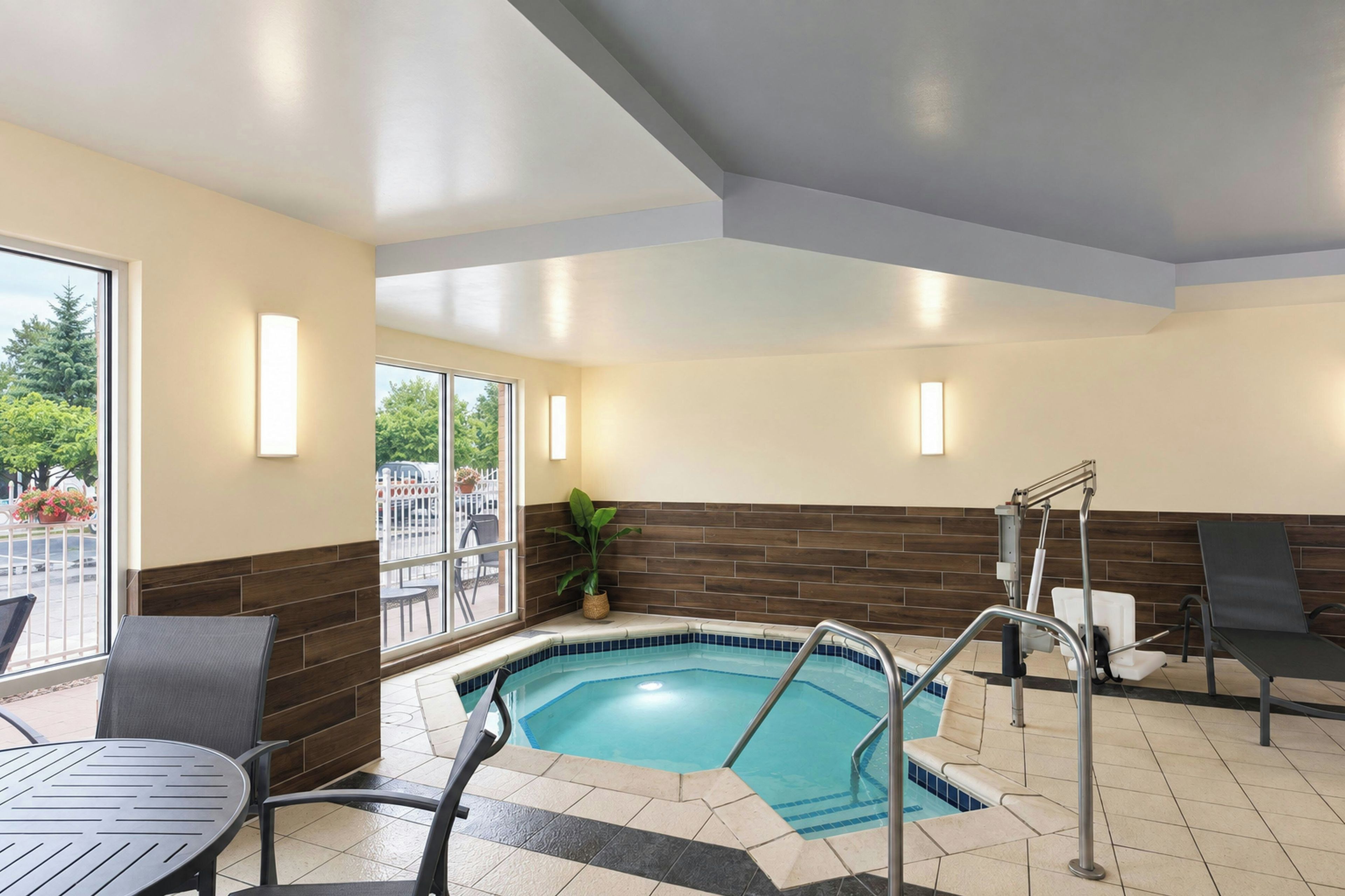 A pool area with a hot tub, seating, and a view of the outdoors.