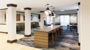 A spacious hotel lobby with a long reception desk, multiple seating areas, and a large window providing natural light. - Fairfield Inn & Suites by Marriott Milwaukee Airport (Oak Creek)