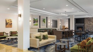 Een moderne lobby met een bank, stoelen, een bar en een open haard.