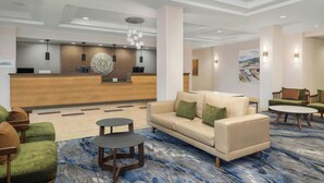 Een hotellobby met een receptiebalie, een zithoek en kunstwerken aan de muren.