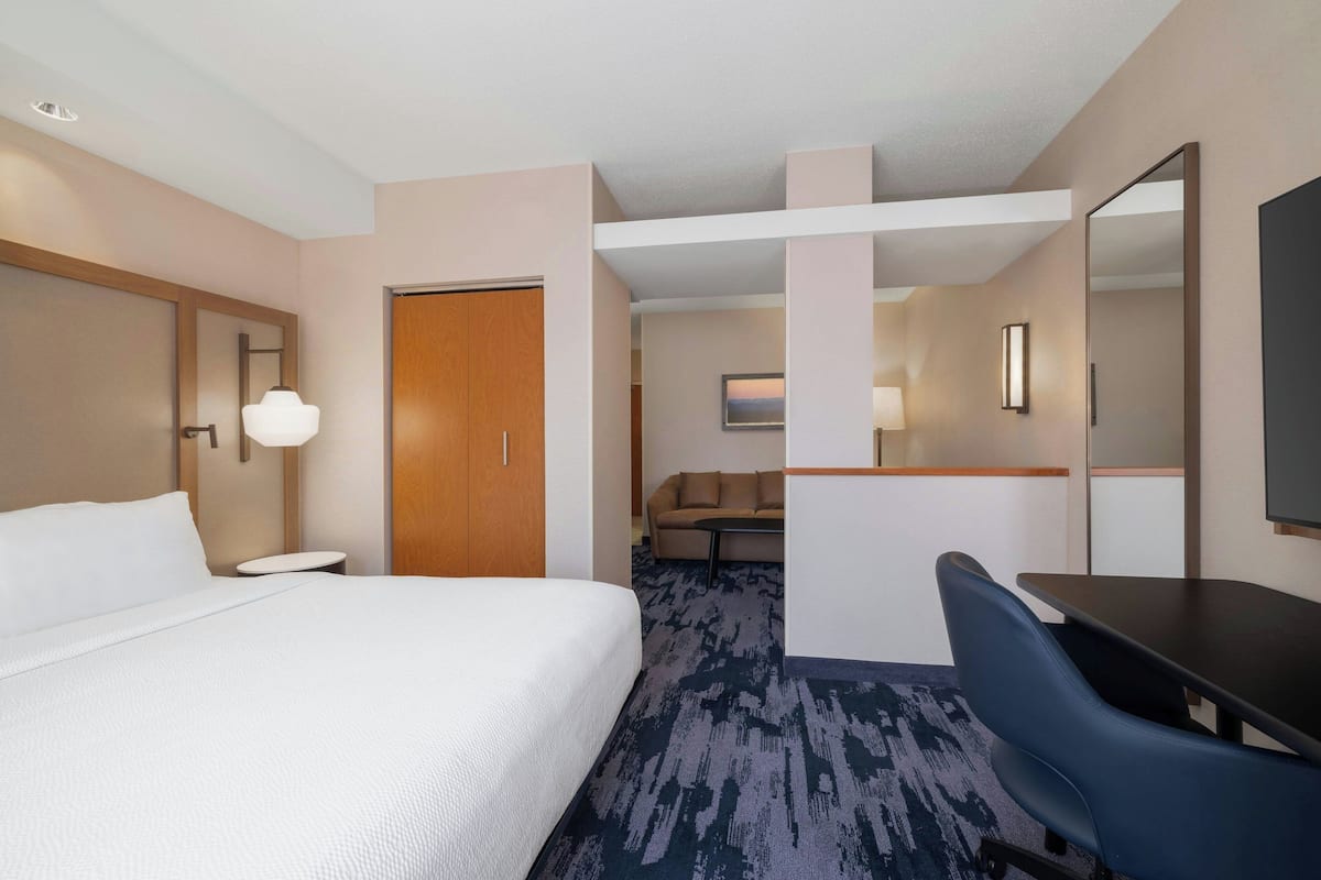 Une chambre d’hôtel avec un grand lit, un bureau, une chaise et un téléviseur.