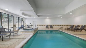 Een binnenzwembad met ligbedden en een jacuzzi.