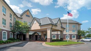 Un hotel con entrada cubierta, bandera estadounidense y fachada de ladrillo.