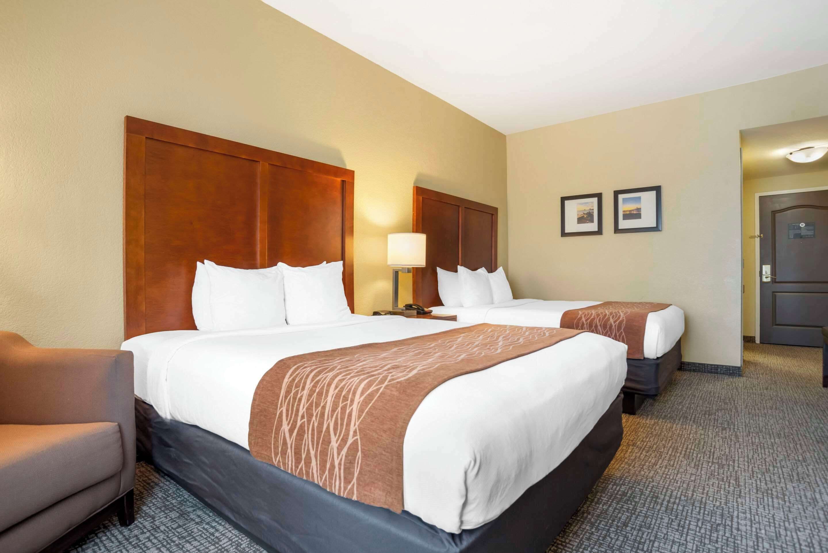 A hotel room with two beds, a desk, and a chair.