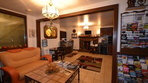 A living room with a sofa, coffee table, and fireplace. There is a kitchen area with cabinets and a refrigerator. - Williamstown Motel (Williamstown)