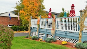 A blue wooden deck with white picket railings, surrounded by a well-maintained lawn and colorful autumn foliage. - Williamstown Motel (Williamstown)