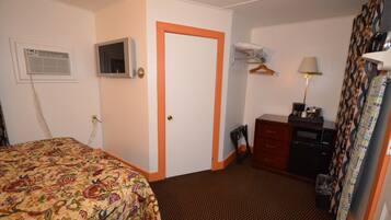 A hotel room with a bed, a dresser, a mirror, a lamp, and a window with curtains.