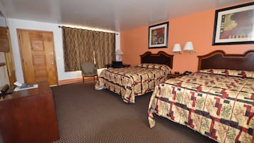 A hotel room with two beds, a desk, a chair, and a door.